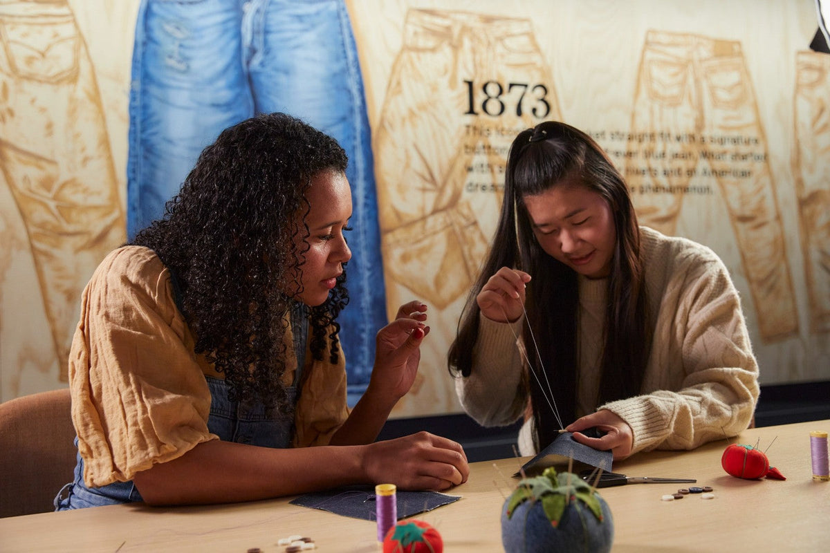 Atelier du Levi’s® Wear Longer Project : deux personnes apprennent à coudre à la main sur du denim